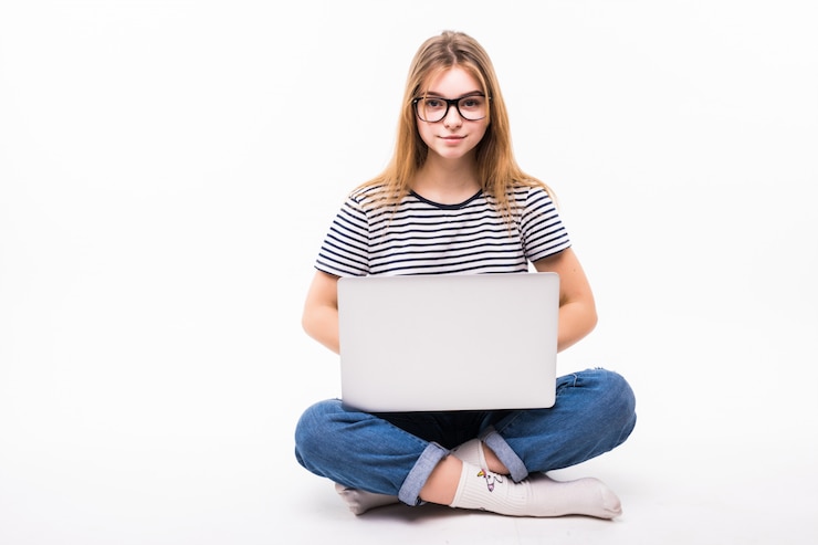 Foto gratuito portátil independiente o de trabajo en casa. hermosa mujer en casual sentarse en el piso y trabajar con una computadora portátil con las piernas cruzadas