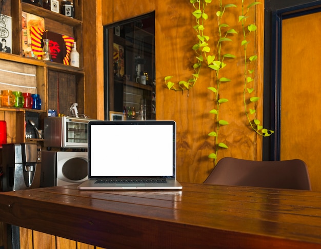 Foto gratuita portátil de pantalla en blanco blanco en mesa de comedor en casa