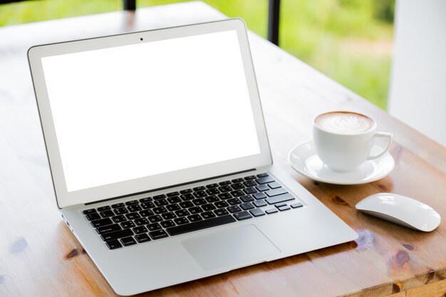 Portátil con pantalla en blanco junto a una taza de café