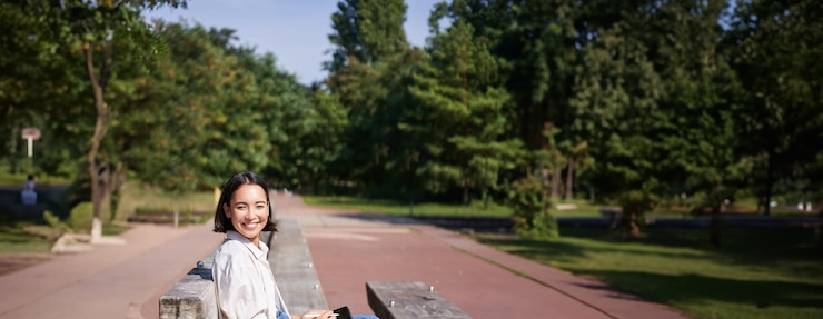 Photo Gratis portrait of young artist asian girl drawing in digital tablet with graphic pen sitting outdoors in