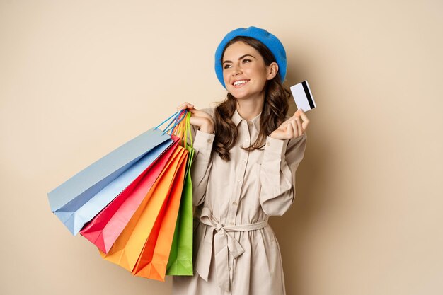 Portrat de chica femenina de moda posando con bolsas de compras de la tienda y pago con tarjeta de c...