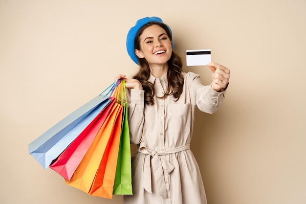 Portrat de chica femenina de moda posando con bolsas de compras de la tienda y pago con tarjeta de c...