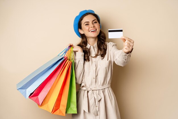 Portrat de chica femenina de moda posando con bolsas de compras de la tienda y pago con tarjeta de c...