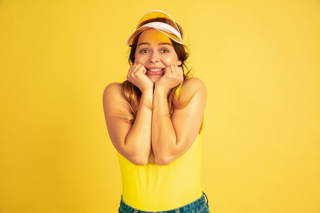 Posando lindo, sonriendo. Retrato de mujer caucásica en estudio amarillo.