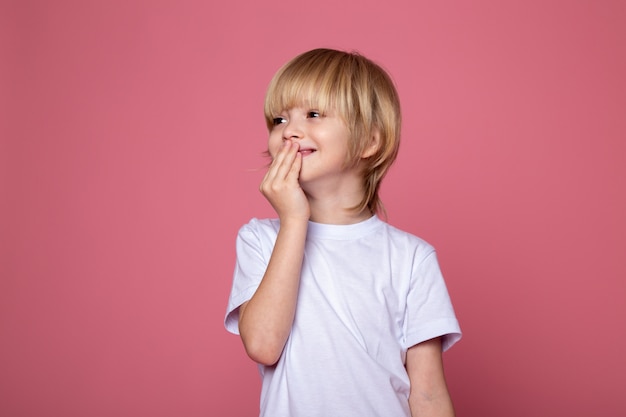 Posando niño sonriendo en camiseta blanca y rosa
