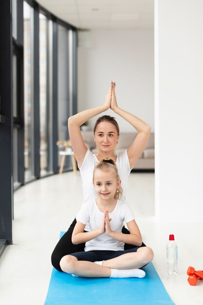 Pose de yoga con madre e hija en casa