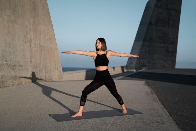 Pose de yoga de mujer de tiro completo al aire libre