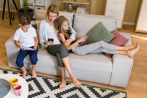 Posibilidad muy remota de la madre y sus niños sentados juntos mirando teléfonos