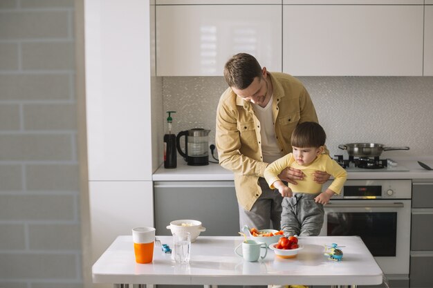 Foto gratuita posibilidad muy remota del padre que detiene a su hijo en la cocina