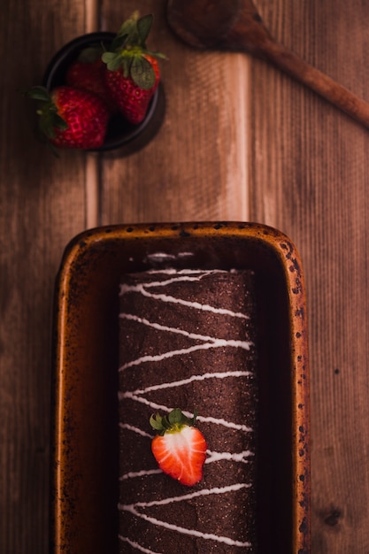 Postre con crema y plato pequeño lleno de fresas