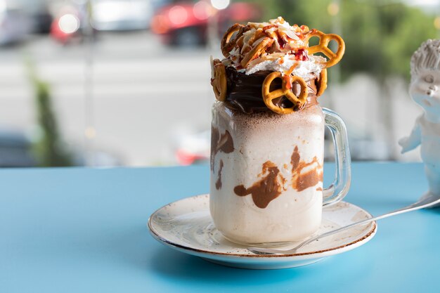 Postre cremoso con chocolate y galletas en la mesa azul