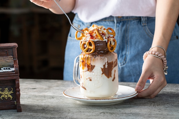 Postre cremoso con chocolate y galletas servido por una mujer