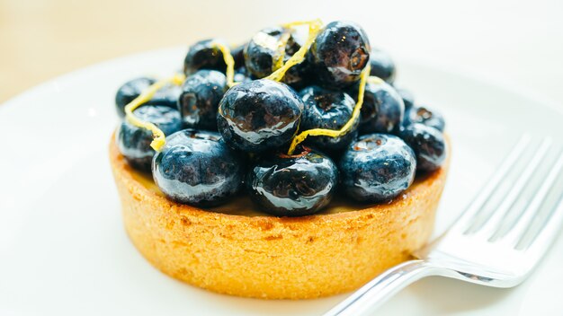 Postre dulce con tarta de arándanos en plato blanco