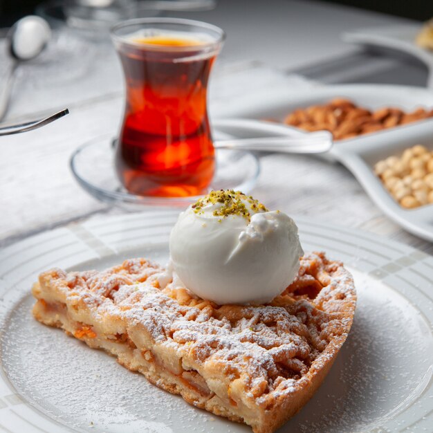 Postre de la opinión de alto ángulo en placa con el té, nueces en el fondo de madera blanco.