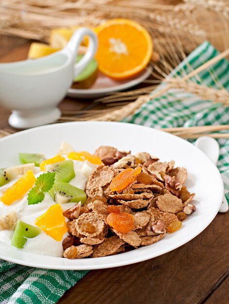 Postre saludable con muesli y fruta en un plato blanco sobre la mesa