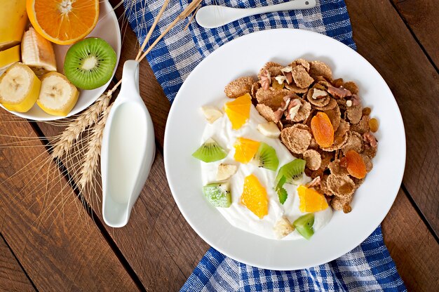 Postre saludable con muesli y fruta en un plato blanco sobre la mesa