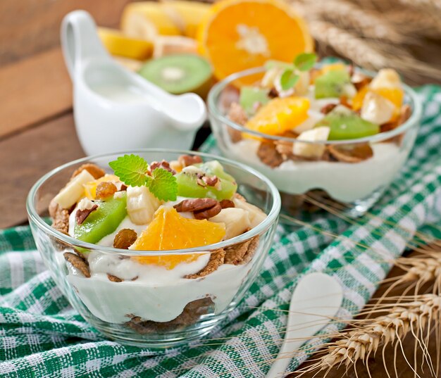 Postre saludable con muesli y fruta en un recipiente de vidrio sobre la mesa