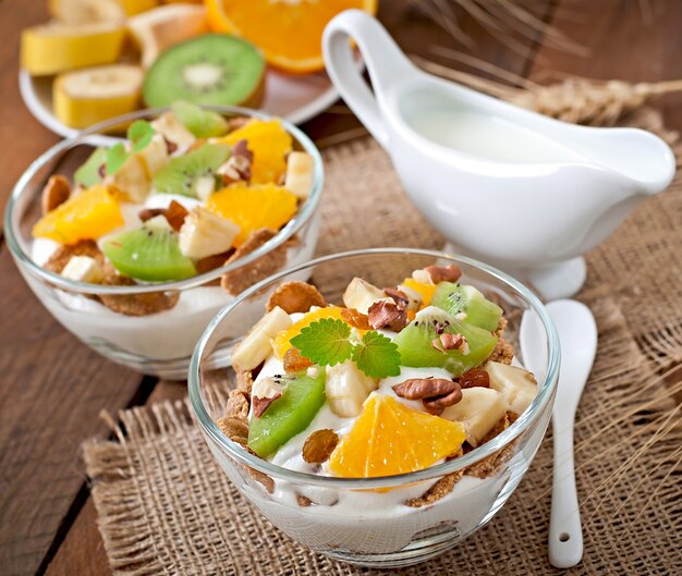 Postre saludable con muesli y fruta en un recipiente de vidrio sobre la mesa