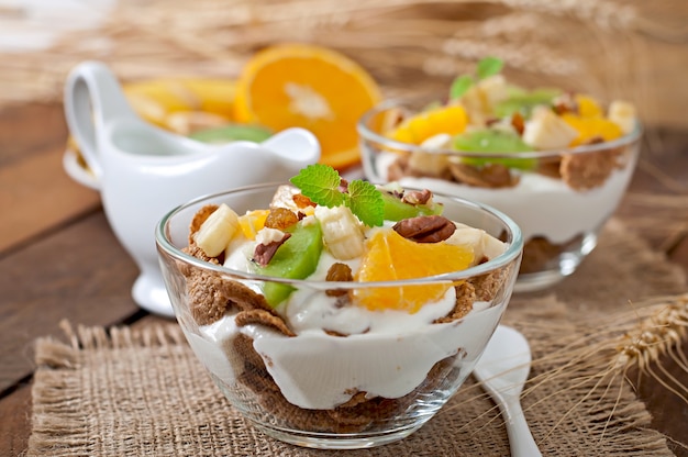 Postre saludable con muesli y fruta en un recipiente de vidrio sobre la mesa