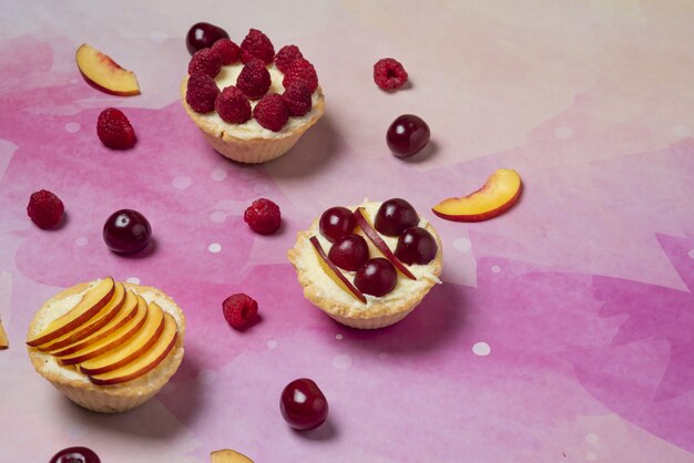 Postres de verano con frutas y bayas en rodajas sobre fondo rosa