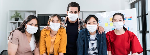 Foto gratuita postura de acción de lucha multirracial de puesta en marcha de pequeñas empresas asiáticas con computadora portátil y papel cuadriculado para todos enmascarados para la protección covid19 gripe corona prevenir ideas saludables concepto fondo de oficina