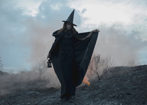 Postura de un hombre con sombrero y ropa de bruja negra