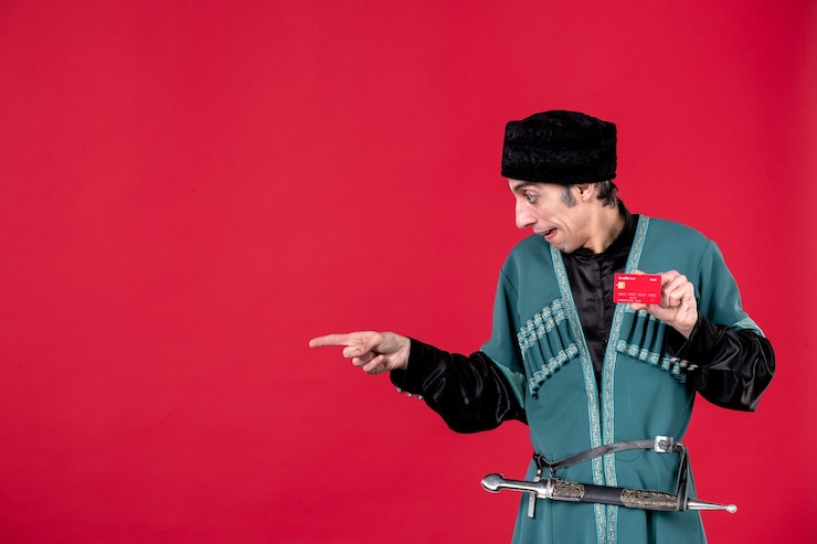 Photo Gratis potret pria azeri muda dengan kostum tradisional memegang kartu kredit di atas warna merah