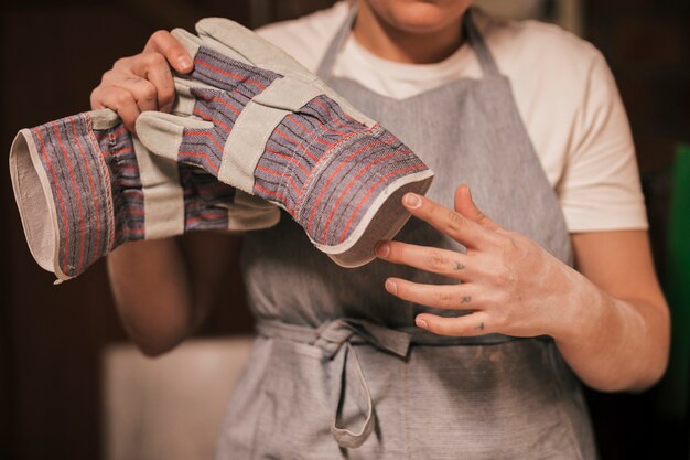 Potter de mujer quitándose los guantes de mano.