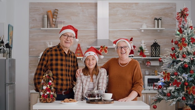 Pov de familia feliz con gorro de Papá Noel saludando a amigos remotos durante la conferencia de videollamada en línea