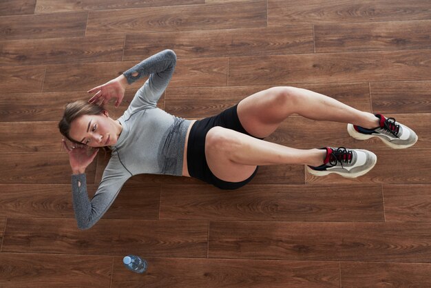 Practicando en el suelo. Deportiva joven tiene día de fitness en el gimnasio por la mañana