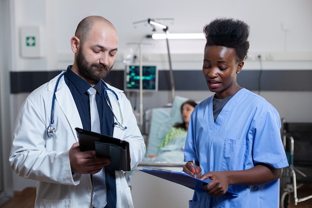 Practicante de hombre discutiendo con asistente negro en la sala del hospital