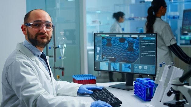 Practicante de laboratorio médico con experiencia sonriendo y mirando a puerta cerrada. Equipo de médicos científicos que examinan la evolución del virus utilizando herramientas de alta tecnología y química para la investigación científica, vacuna