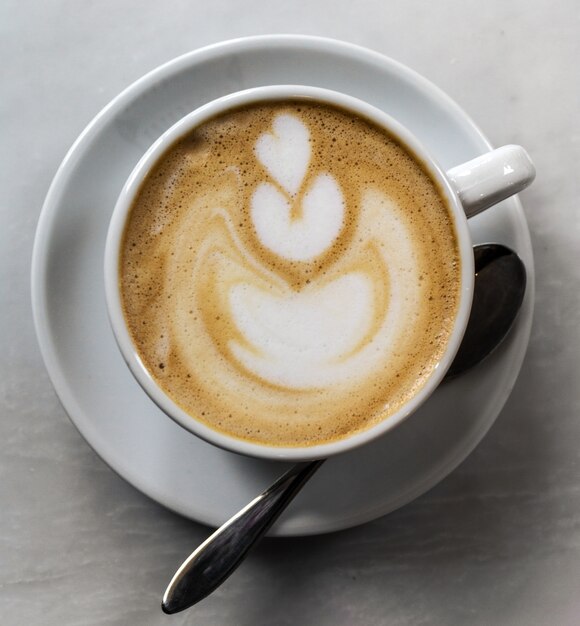 Precioso sabroso café cappuccino en blanco taza con cuchara en la pestaña