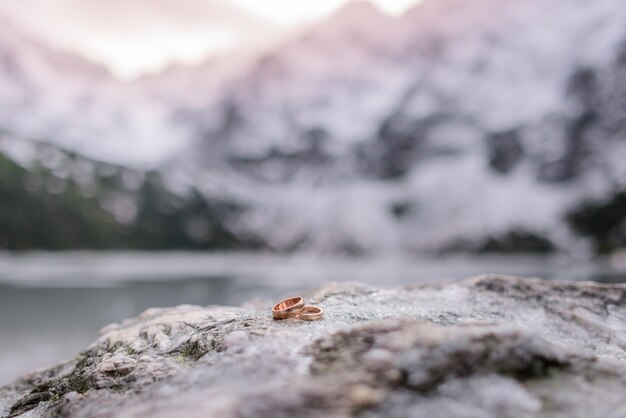 Preciosos anillos de boda están tumbados en la piedra gris al aire libre, concepto de matrimonio