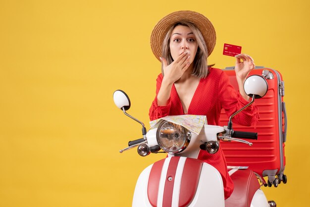 Se preguntó señorita en vestido rojo con tarjeta de crédito cerca de ciclomotor