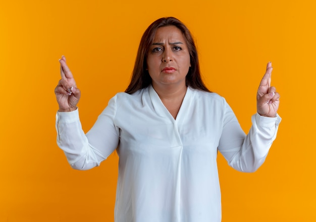 Foto gratuita preocupada casual mujer de mediana edad caucásica cruzando los dedos