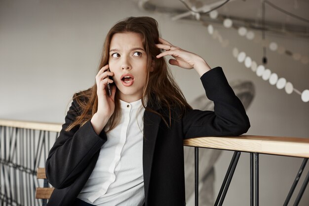 Preocupada joven empresaria en el café hablando por teléfono