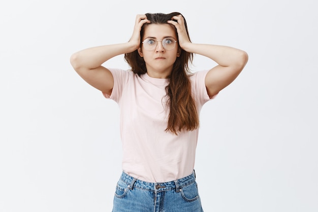 Foto gratuita preocupado ansioso joven morena con gafas posando