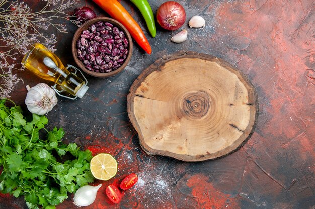 Preparación de la cena con alimentos y botella de aceite de frijoles y un manojo de tomate limón verde y bandeja de madera en la mesa de colores mezclados