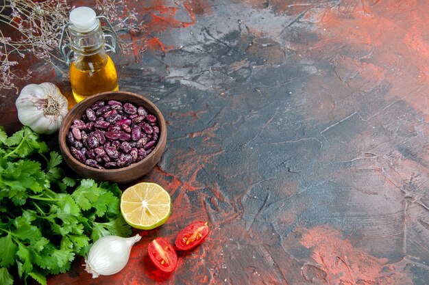 Preparación de la cena con alimentos y botella de aceite de frijoles y un manojo de tomate limón verde en una mesa de colores mezclados