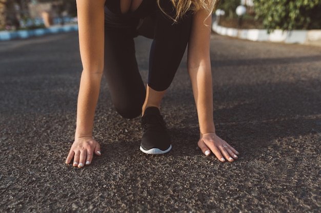 Preparación para correr, inicio de mujer bonita, manos cerca de los pies en zapatillas de deporte en la calle. Motivación, mañana soleada, estilo de vida saludable, recreación, entrenamiento, trabajo a domicilio