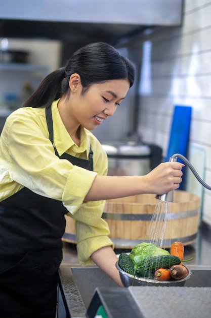 Preparación. Mujer en la cocina lavando verduras antes de cocinar