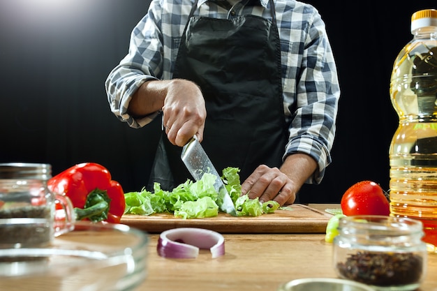 Preparando ensalada. Chef mujer cortando verduras frescas.