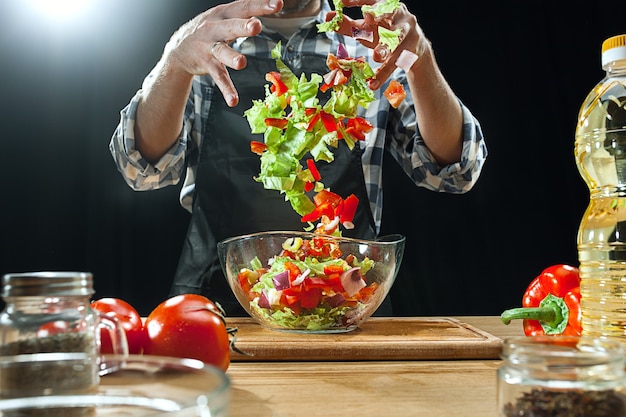 Preparando ensalada. Chef mujer cortando verduras frescas.