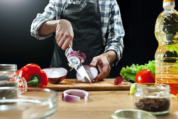 Preparando ensalada. Chef mujer cortar verduras frescas.