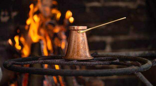 Prepare café en un turco en un fuego abierto. El concepto de un ambiente acogedor y bebidas.