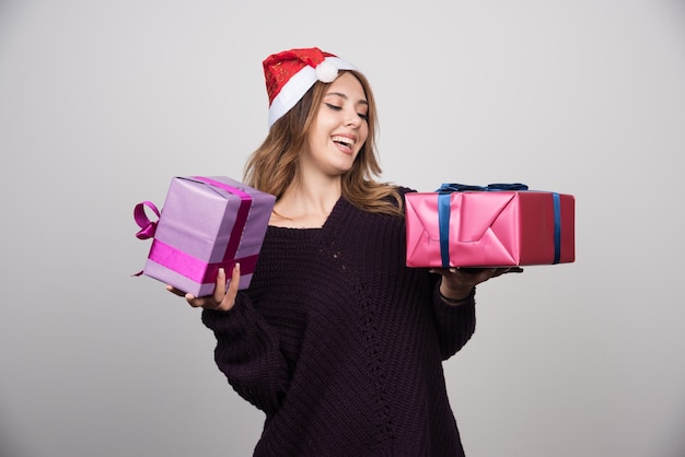 Presenta mujer joven con sombrero de Santa con cajas de regalo.