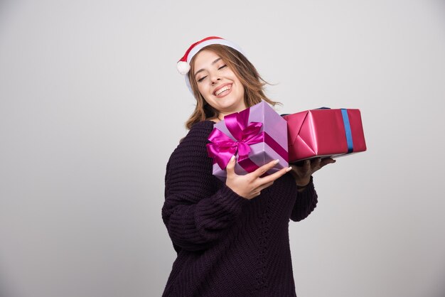 Presenta mujer joven con sombrero de Santa con cajas de regalo.