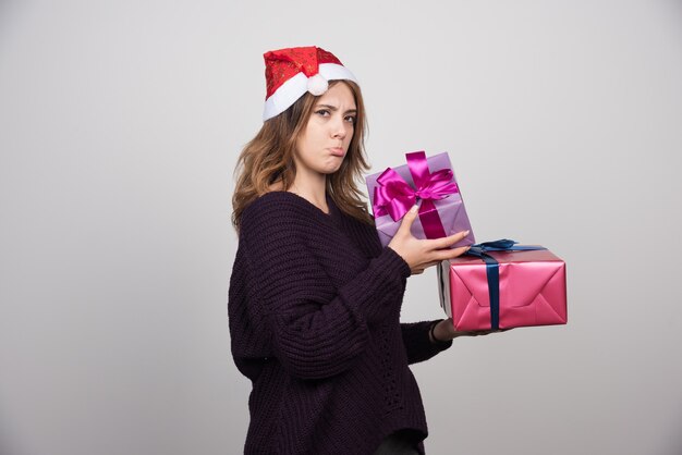 Presenta mujer joven con sombrero de Santa con cajas de regalo.