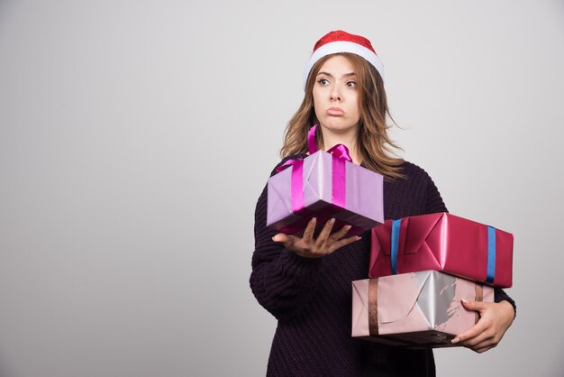 Presenta mujer joven con sombrero de Santa con cajas de regalo.